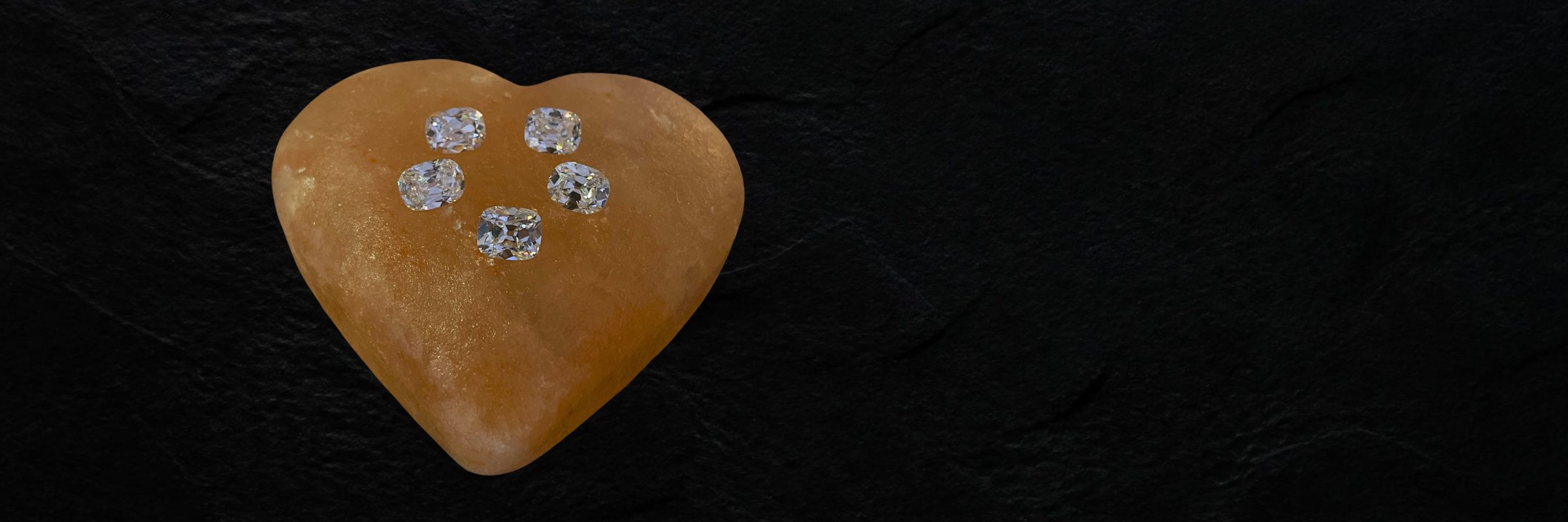Five cushion-cut diamonds resting on a rose-quartz heart