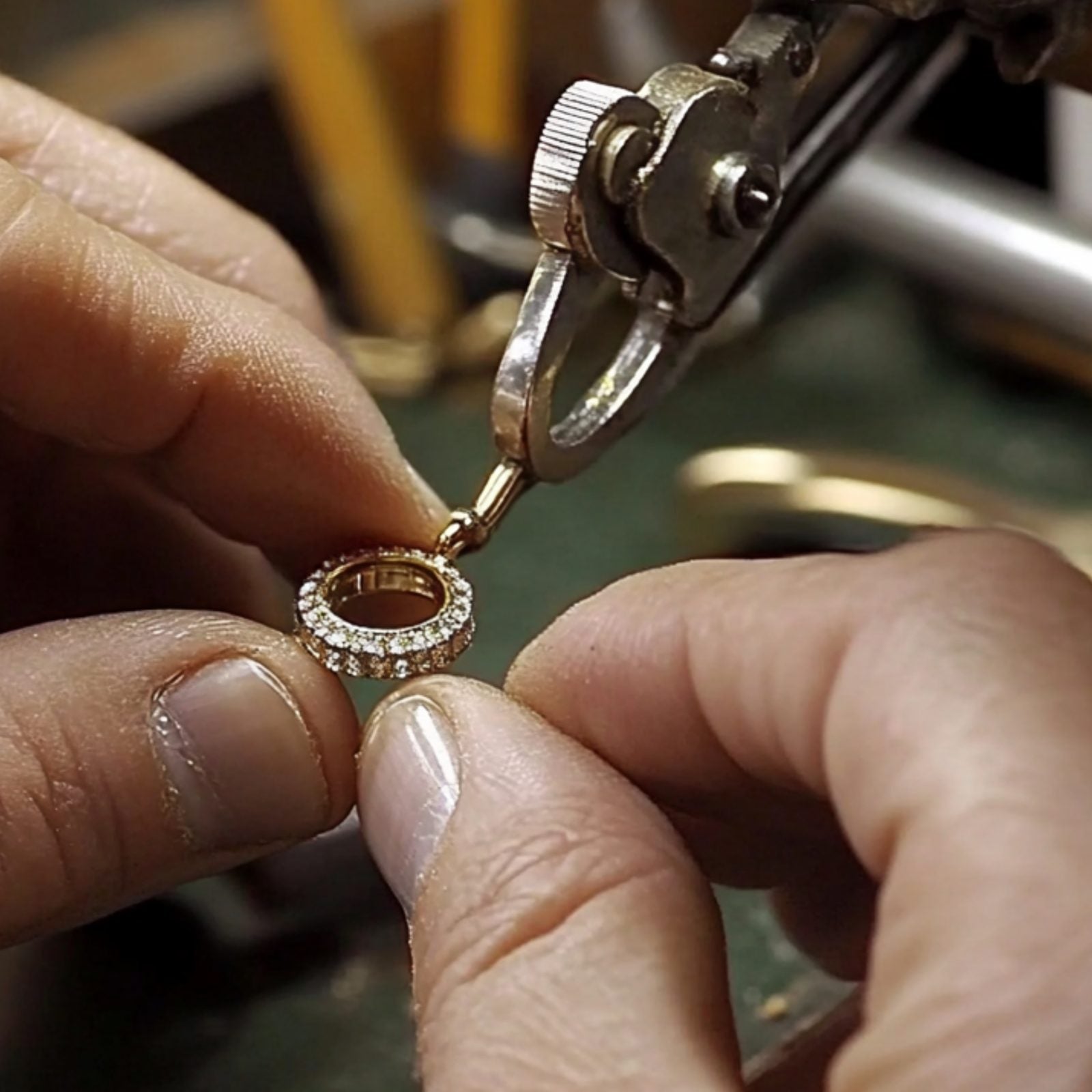 The Crafting — jeweler's hands setting diamonds into a gold pavé band at the bench