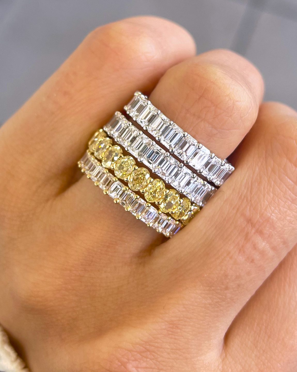 A hand wearing stacked eternity bands in white and yellow gold